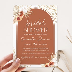 May include: A bridal shower invitation featuring a terracotta arch design. The text reads "bridal SHOWER" and includes details for Samantha Donovan's shower on August 24th at 3:00 PM. Floral accents and gold glitter complete the design.