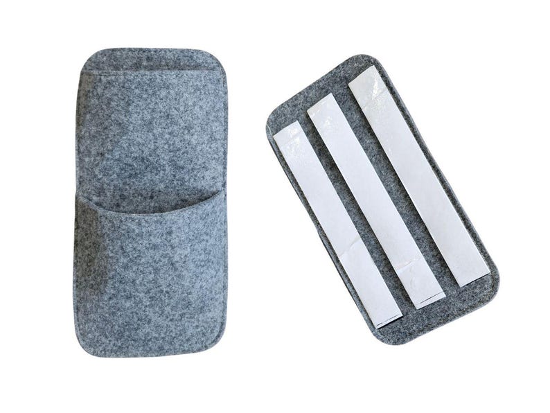May include: Two gray felt organizers. One is a pocket-style wall organizer with a rounded top and a curved pocket. The other is a rectangular felt piece with three adhesive strips on the back for mounting.