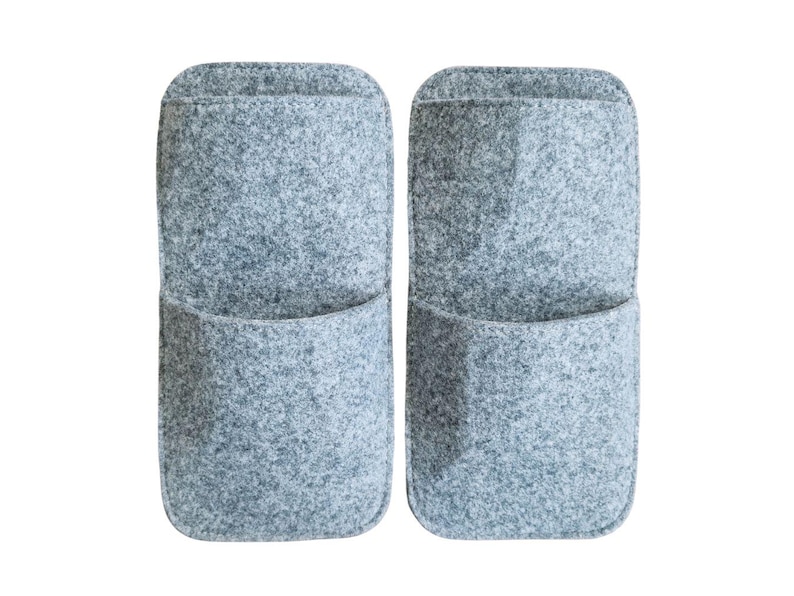 May include: Two gray felt wall organizers with a pocket design. The organizers are rectangular with rounded tops and a single pocket on the front. The felt material has a speckled texture, and the background is white.
