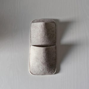 May include: A rectangular, light gray felt wall organizer with two pockets. The top pocket is larger and open, while the bottom pocket is smaller. The organizer is made of soft felt material and has a rounded top and bottom.