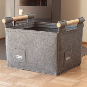 May include: A gray felt storage bin with wooden handles. The bin has two small pockets on the front, each with a white label that says "Click Happy".