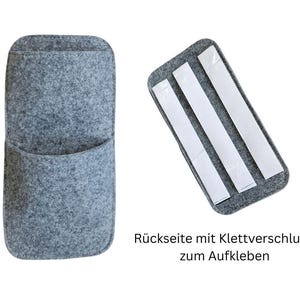May include: A gray felt pocket organizer with a rounded top and a curved pocket. The back of the organizer has a rectangular felt piece with three adhesive strips for mounting. Text in German reads: "Back with Velcro to stick on."