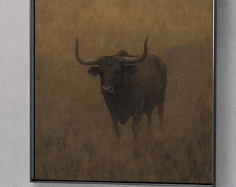 May include: Framed artwork featuring a dark bull standing in a field. The bull has large horns and a dark coat, set against a warm, golden-brown background. The artwork is encased in a black frame, suitable for home decor.