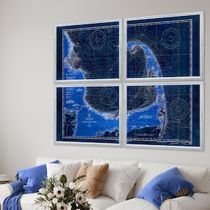 May include: A set of four nautical charts of Cape Cod Bay, printed in blue and white, framed in white and displayed on a white wall above a white couch with blue throw pillows.