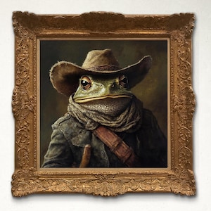 May include: A framed painting of a green frog wearing a cowboy hat and a brown scarf. The frog is looking directly at the viewer. The painting is in a gold frame with ornate details.