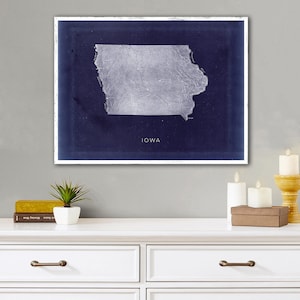 May include: A vintage-style map of Iowa with a navy blue background and a white outline of the state. The word "Iowa" is printed in white at the bottom of the map.