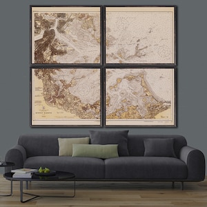 May include: A set of four vintage nautical maps in black frames, depicting the Boston Harbor area. The maps are printed in brown and beige tones on a white background. The maps are arranged in a grid pattern on a gray wall above a gray couch.