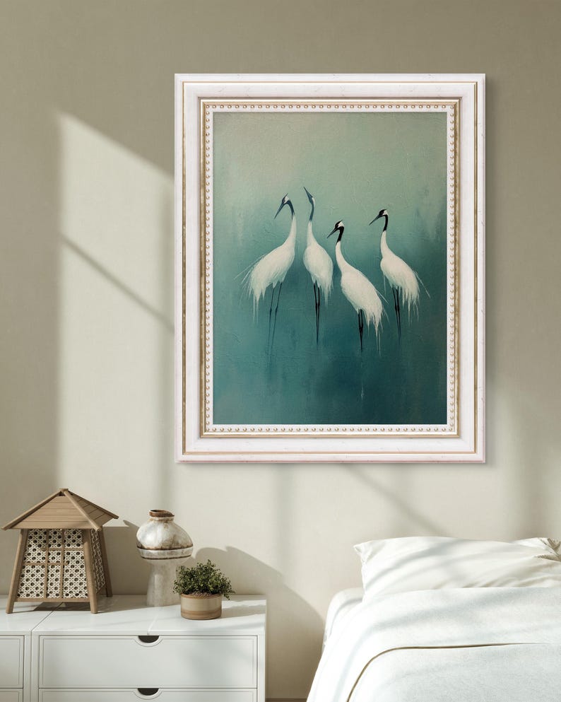 May include: A framed painting of four white cranes with black markings on a teal background. The frame is white with a gold trim.