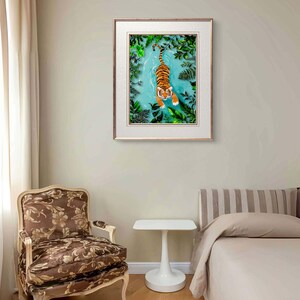 May include: A framed print of a tiger swimming in a turquoise blue pool of water surrounded by green foliage.