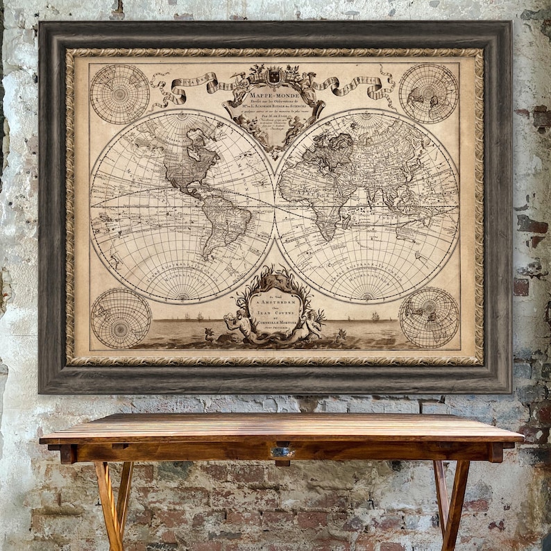 May include: A framed vintage world map print in brown tones with a decorative border. The map is titled "Mappe Monde" and features a detailed depiction of the continents and oceans. The map is surrounded by a decorative border with a crest and scrollwork.