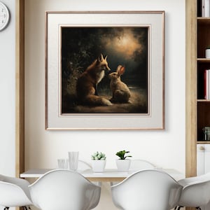 May include: Framed artwork featuring a fox and a rabbit in a forest setting. The fox has reddish-brown fur, and the rabbit is light brown. The artwork is framed in a gold-colored frame and hangs above a white table with white chairs.