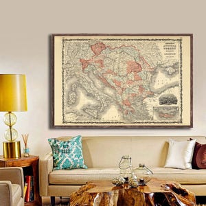 May include: A vintage map of Austria, Turkey, and Greece. The map is printed in black and white with red and pink highlights. The map is framed in a brown wooden frame.