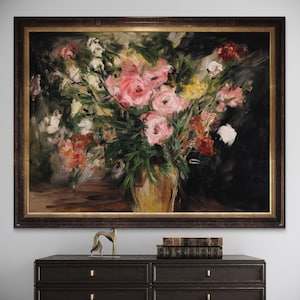 May include: A framed floral still life painting featuring a bouquet of pink, white, yellow, and red flowers in a gold vase. The artwork has a dark brown frame and is displayed on a dark brown dresser.