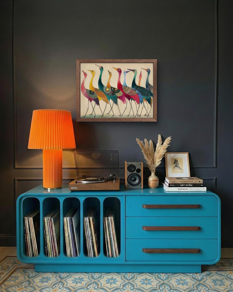 May include: A teal blue cabinet with a built-in record player, orange lamp, and framed artwork of colorful birds. The cabinet has open slots for vinyl records and drawers with wooden handles. A small speaker and decorative vase are also on top.