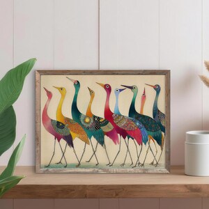 May include: A framed art print featuring a line of colorful birds with long necks and legs. The birds have a variety of colors, including red, yellow, blue, and green, with patterned details on their bodies. The artwork is displayed on a wooden shelf.