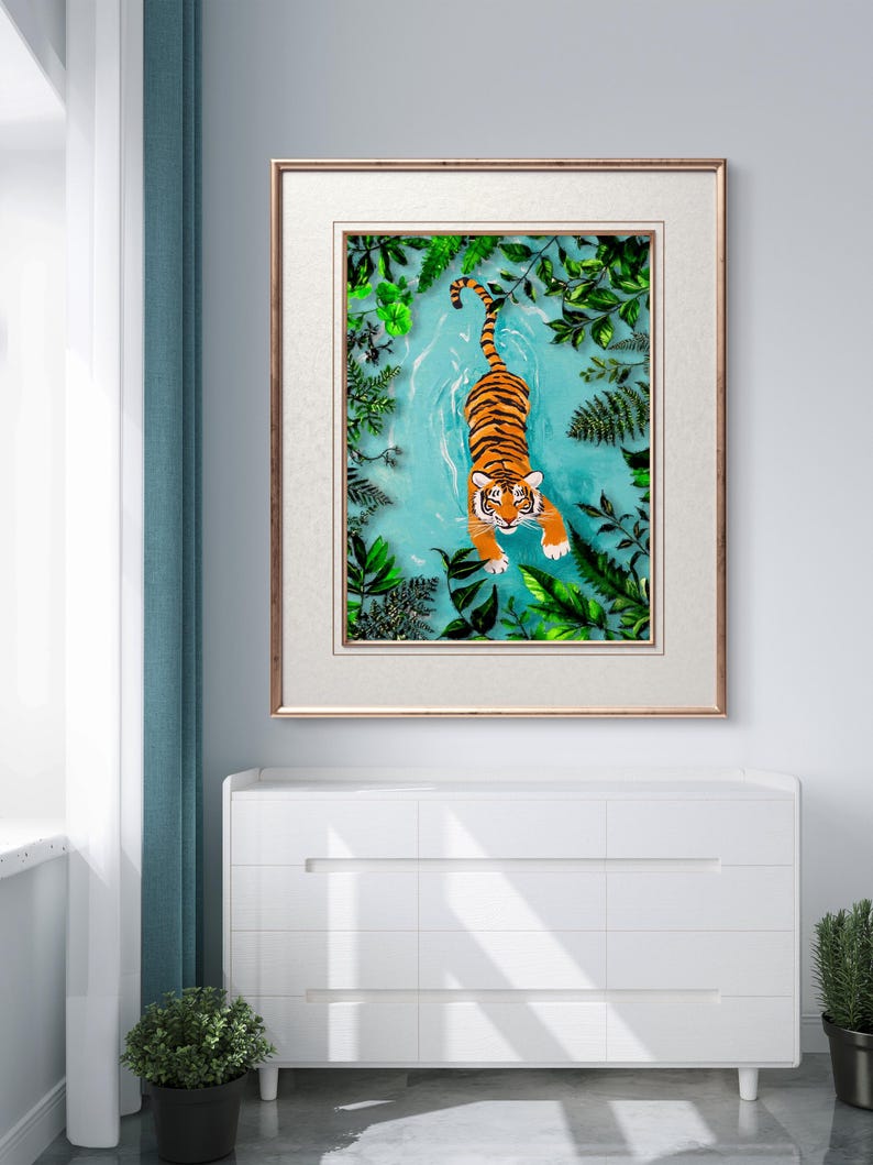 May include: A framed illustration of a tiger swimming in a turquoise blue body of water surrounded by green foliage.
