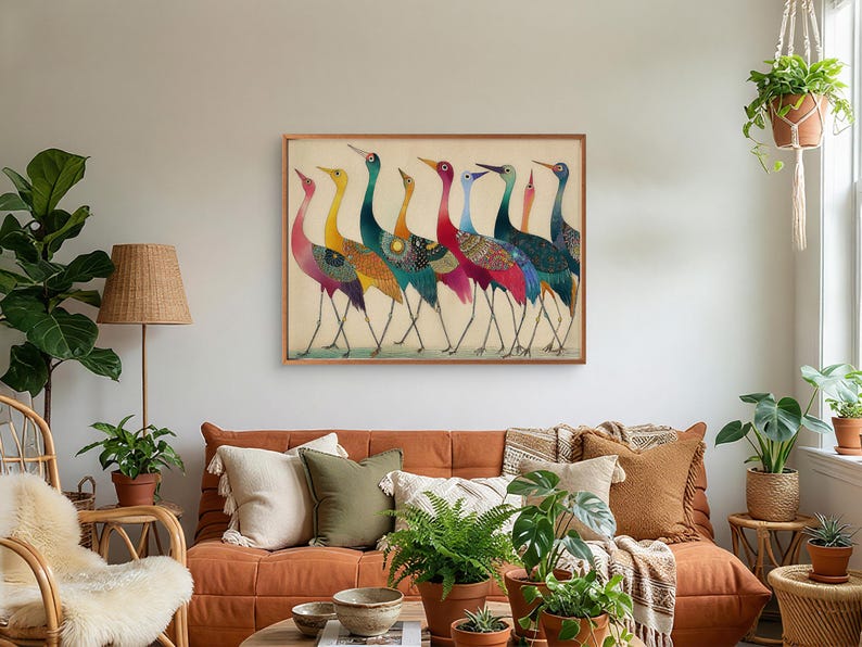 May include: A framed art print featuring a line of colorful birds with long legs and necks. The birds have a variety of colors, including red, yellow, blue, and green. The artwork is displayed in a living room setting with a brown sofa and plants.