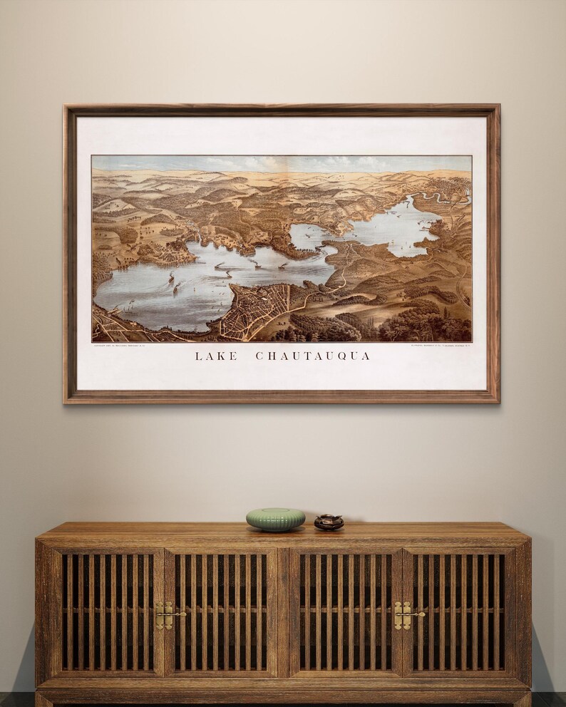 Puede incluir: Un mapa vintage enmarcado del lago Chautauqua, Nueva York, con un marco de madera marr&oacute;n y un passe-partout blanco. El mapa muestra el lago y el &aacute;rea circundante en detalle, con carreteras, edificios y otras caracter&iacute;sticas etiquetadas.