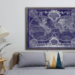May include: A vintage world map print in white on a dark blue background. The map is framed and hanging on a white wall above a gray couch with pillows.