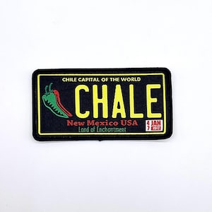 May include: Black rectangular patch with yellow border and text. The patch reads "CHALE" in yellow, with a green and red chili pepper graphic. Text includes "CHILE CAPITAL OF THE WORLD", "New Mexico USA", "Land of Enchantment", and the date "4 JAN 1912".