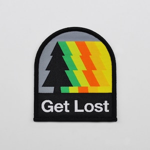 May include: A black and gray patch with a stylized green, yellow, and orange tree design. The text "Get Lost" is printed in white below the tree.