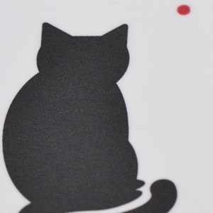 May include: A black silhouette of a cat sitting with its tail curled around its legs. The cat is facing away from the viewer and is looking to the right. There is a small red dot in the top right corner of the image.