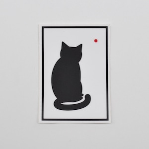 May include: A black silhouette of a cat sitting with its tail curled around its body. The cat is on a white background with a small red dot in the top right corner.