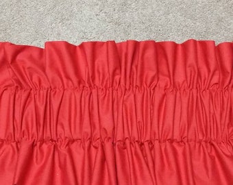 May include: Red fabric with a gathered ruffle along the bottom edge.