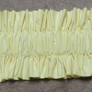May include: A yellow fabric ruffle trim with a gathered and pleated design. The trim is made of a soft, lightweight fabric and has a delicate, feminine look.