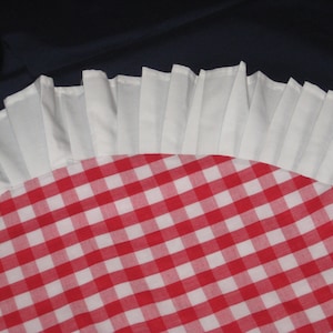 May include: A red and white gingham tablecloth with a white ruffled edge.