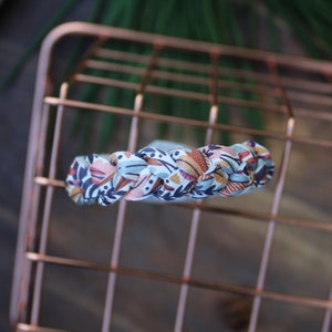 May include: A braided headband with a blue, brown, and pink floral pattern.