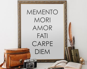 May include: A framed print with the text "MEMENTO MORI AMOR FATI CARPE DIEM" in black lettering on a white background. The frame is gold and ornate. The print is sitting on a table with a brown leather bag, a camera, a book, and a few decorative items.