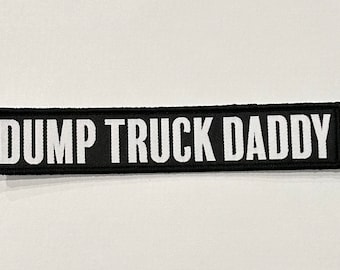 Può includere: Toppa nera e bianca con il testo "DUMP TRUCK DADDY" in lettere bianche.