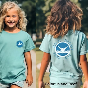 May include: A light blue t-shirt with a blue circle graphic on the front and back. The graphic features a swimmer in the water with the words "Back Free Breast Fly" around the circle. The shirt is called "Island Reef".