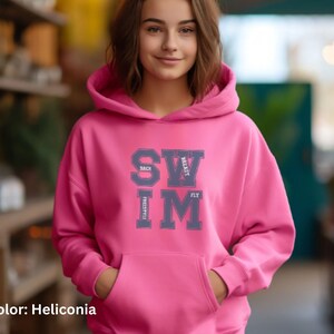 May include: A pink hoodie with a front pocket and a drawstring hood. The hoodie features the word "SWIM" in a collegiate-style font, with the words "BACK", "BREAST", "FLY", and "FREESTYLE" arranged around it. The color is Heliconia.