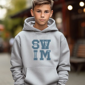 May include: A light gray hoodie with a front pocket and a drawstring hood. The front of the hoodie features the word "SWIM" in a blue, collegiate-style font, with "BACK", "BREAST", "FREESTYLE", and "FLY" arranged around the letters.
