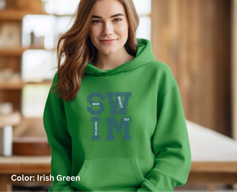 May include: Irish green hoodie with the word SWIM in large, teal letters. The words BACK, BREAST, FREESTYLE, and FLY are stacked around the SWIM letters. The hoodie has a drawstring hood and a front pocket.