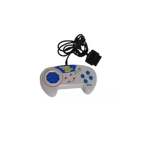 Puede incluir: Un mando Turbo Touch 360 blanco y gris con cable y conector negros. El mando tiene botones azules y una almohadilla central azul. El texto "Turbo Touch 360" es visible.