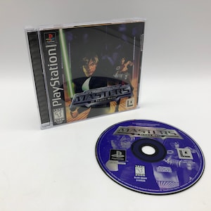 Puede incluir: Una caja de juego de PlayStation y un disco para Star Wars: Masters of Teras Kasi. La caja es negra con una imagen de un personaje del juego. El disco es morado con el título y el logotipo del juego.