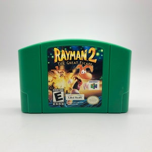 May include: Green Nintendo 64 game cartridge for Rayman 2: The Great Escape. The front of the cartridge features a colorful image of Rayman and other characters from the game. The game is rated E for Everyone by the ESRB.