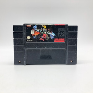 Puede incluir: Un cartucho de juego Super Nintendo negro con una etiqueta que muestra un personaje azul y rojo con el título "Killer Instinct" en letras blancas.