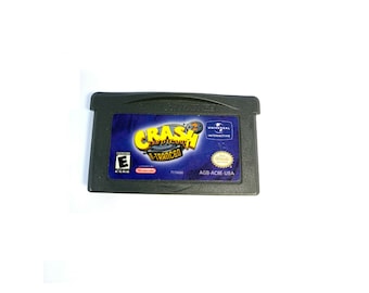 May include: A black Game Boy Advance game cartridge for Crash Bandicoot: The Wrath of Cortex. The game cartridge has a blue and yellow label with the game title and a rating of "E" for Everyone. The label also includes the Universal Interactive logo and the words "AGB-ACBE USA".