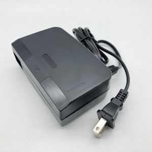 May include: A black Nintendo 64 power adapter with a black power cord and a US plug.