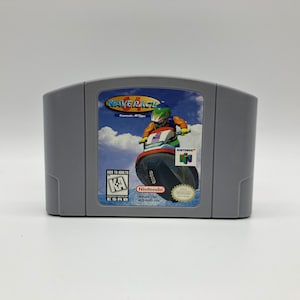 May include: A gray Nintendo 64 game cartridge for Wave Race 64. The front of the cartridge features a blue and white jet ski with a rider wearing a green and orange wetsuit. The game is rated "K-A" for Kids to Adults by the ESRB.
