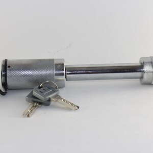 May include: A silver hitch lock with a black cap and two keys. The lock has a threaded end and a smooth, cylindrical body.