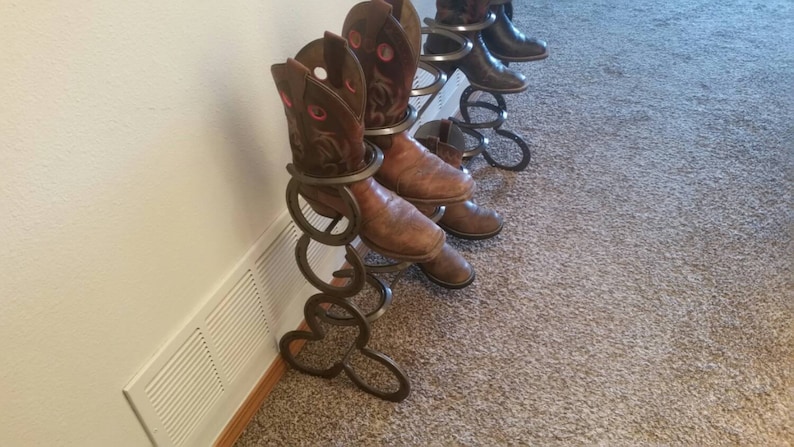 May include: A metal boot rack made of horseshoes, with brown cowboy boots on it.