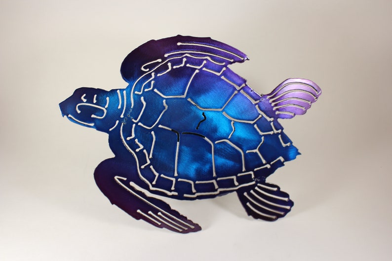 May include: A metal sea turtle sculpture with a blue and purple ombre finish. The turtle is in a swimming pose with its flippers outstretched.