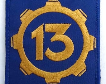May include: A blue fabric patch with a gold embroidered gear and the number 13 inside.