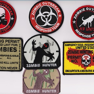 May include: A collection of six embroidered patches featuring zombie-themed designs. The patches are circular and rectangular, with red, black, white, yellow, and green colors. The patches feature text such as "Zombie Outbreak Response Team", "K9 Unit", "Zombie Hunter", and "Hunting Permit".