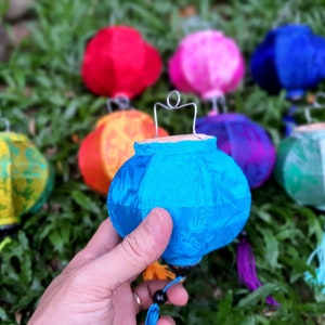Può includere: Assortimento di lanterne di seta colorate con disegni intricati. Le lanterne sono appese a un filo e sono in varie tonalità di rosso, rosa, blu, verde e giallo.